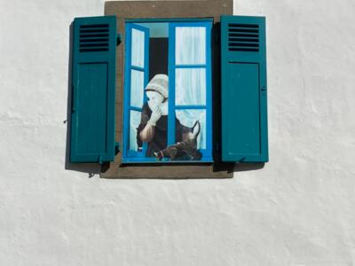 Breton woman in a headdress at the window — Street art in Le Croisic