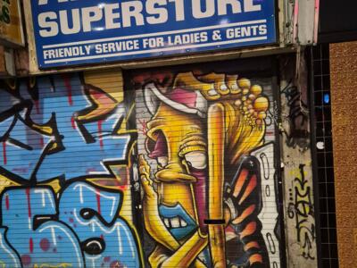 Personnage jaune sur rideau de fer — Street art à Manchester