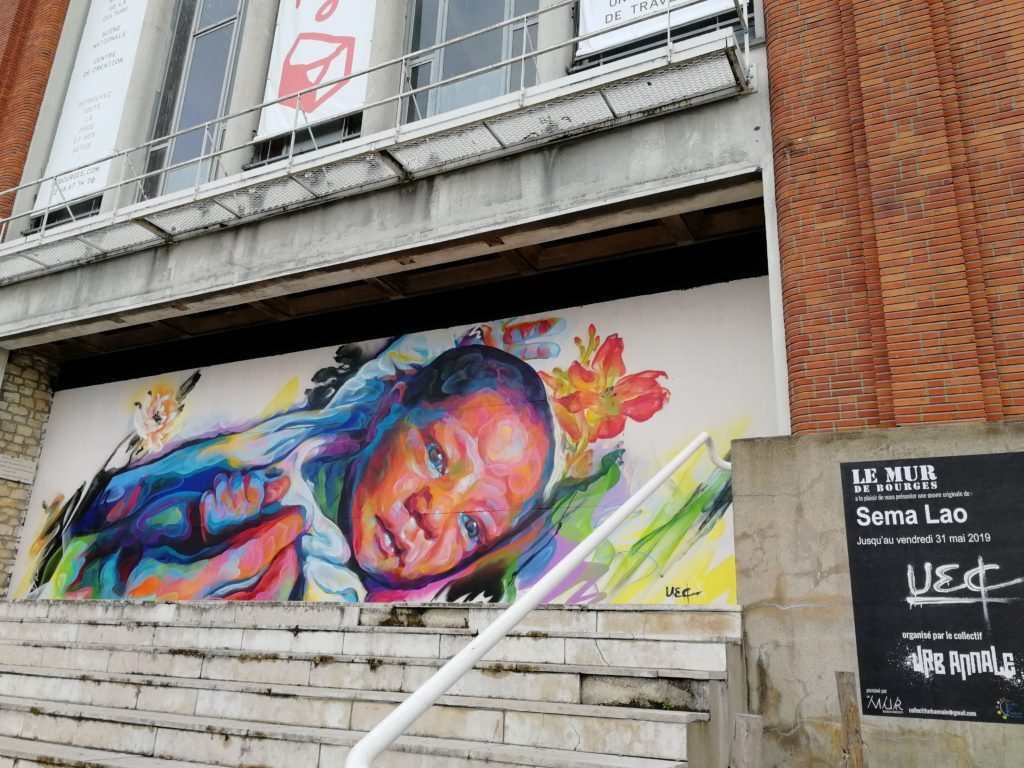 The mural of Sêma Lao, his little girl in the hands of his dad