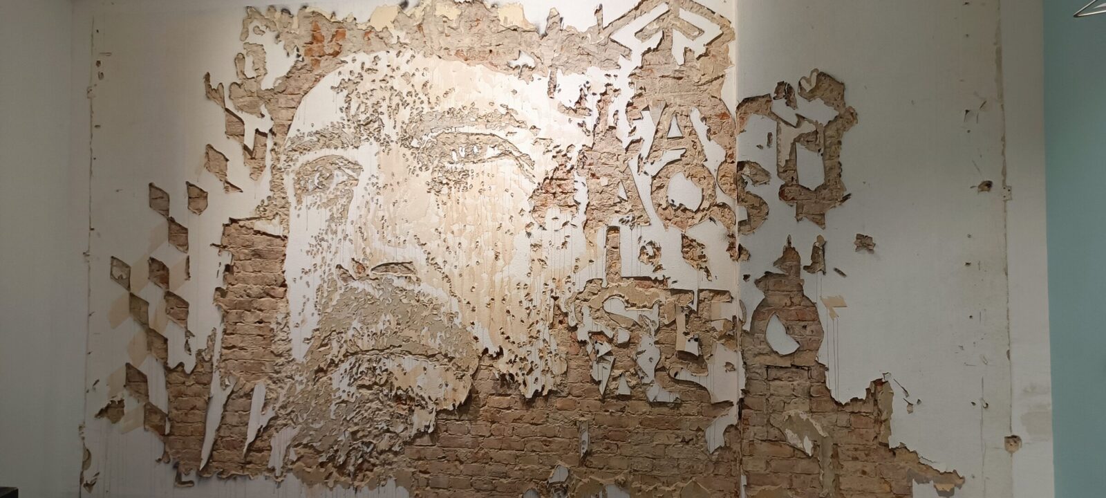 A wall carved by Vhils: the face is not painted, it is exposed brick.
