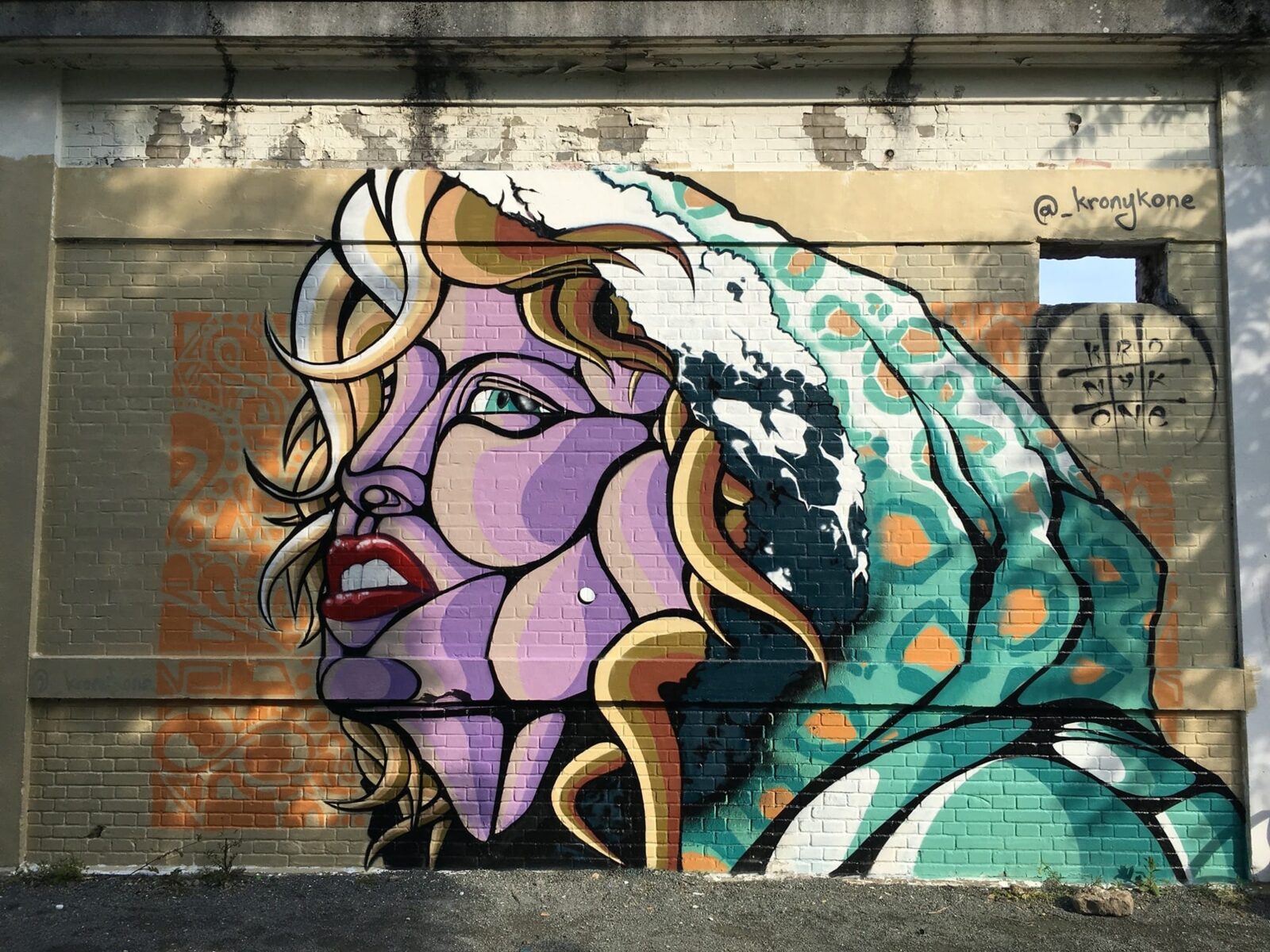 Pop portrait of a woman by Kronyk One, on a brick wall of the southern building.